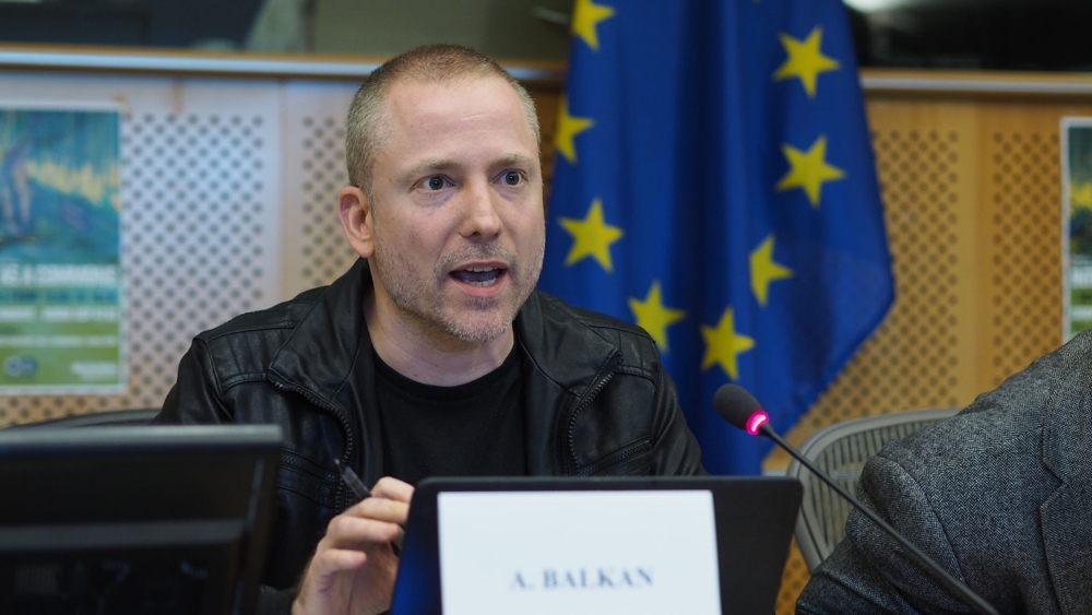 Aral speaking at the European Parliament in front of an EU flag